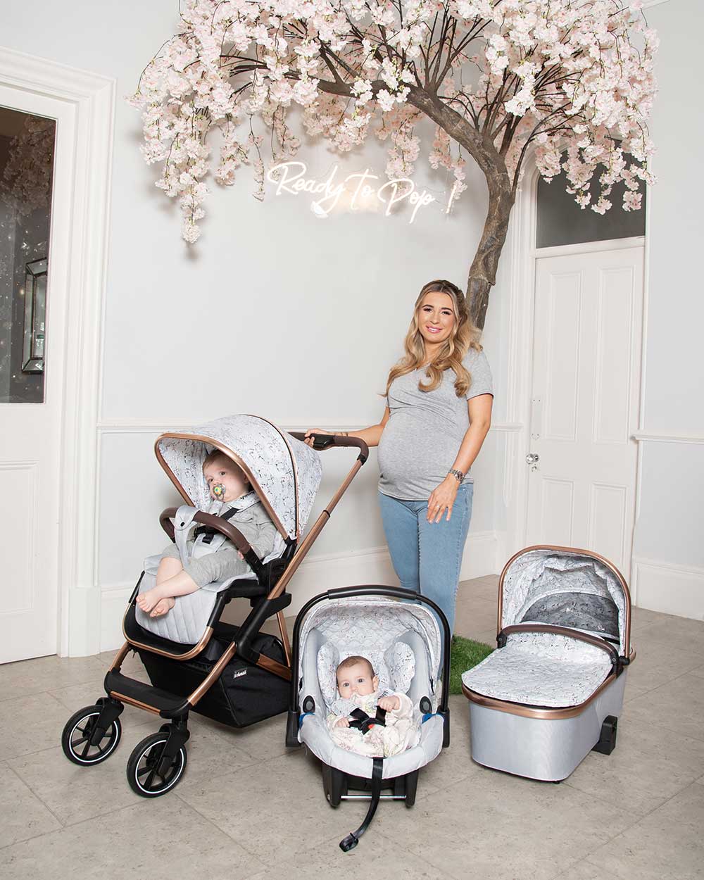 Dani Dyer standing next to a push chair and a carry cot