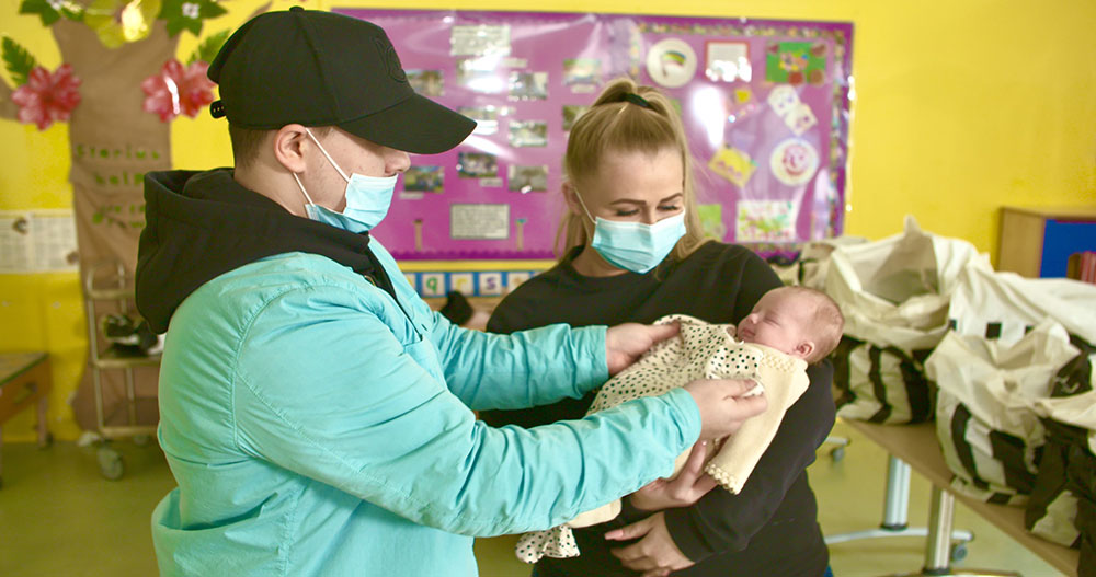 A young couple checking the size of the clothing against their baby