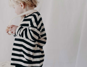 A young boy wearing a long sleeve black and white striped t-shirt