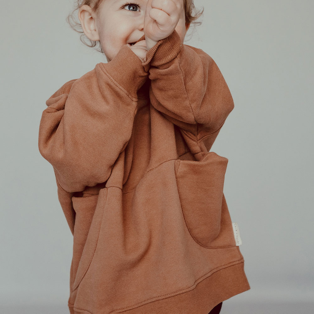 A young girl stood up wearing a oversized jumper