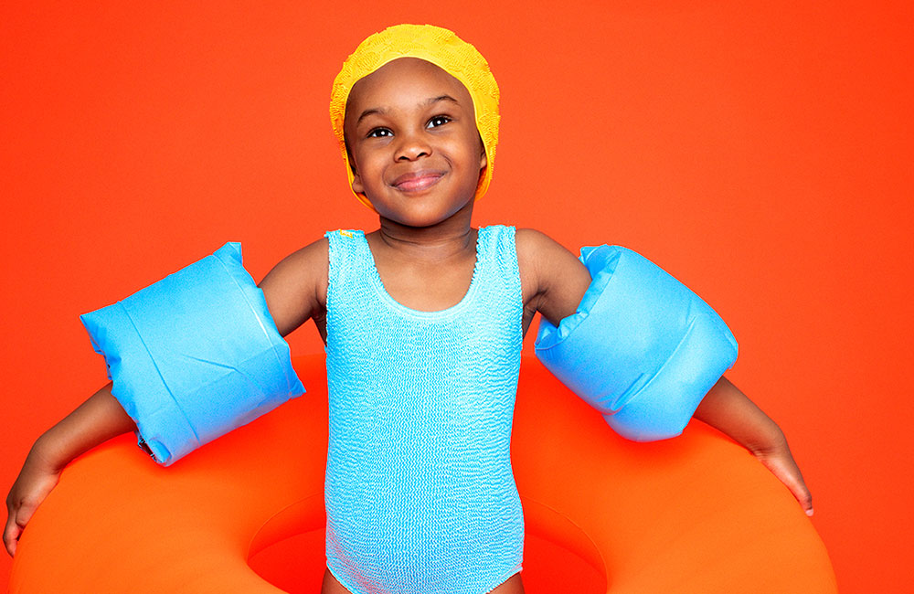 young girl in pale blue mini maxx swimwear with yellow swimming cap