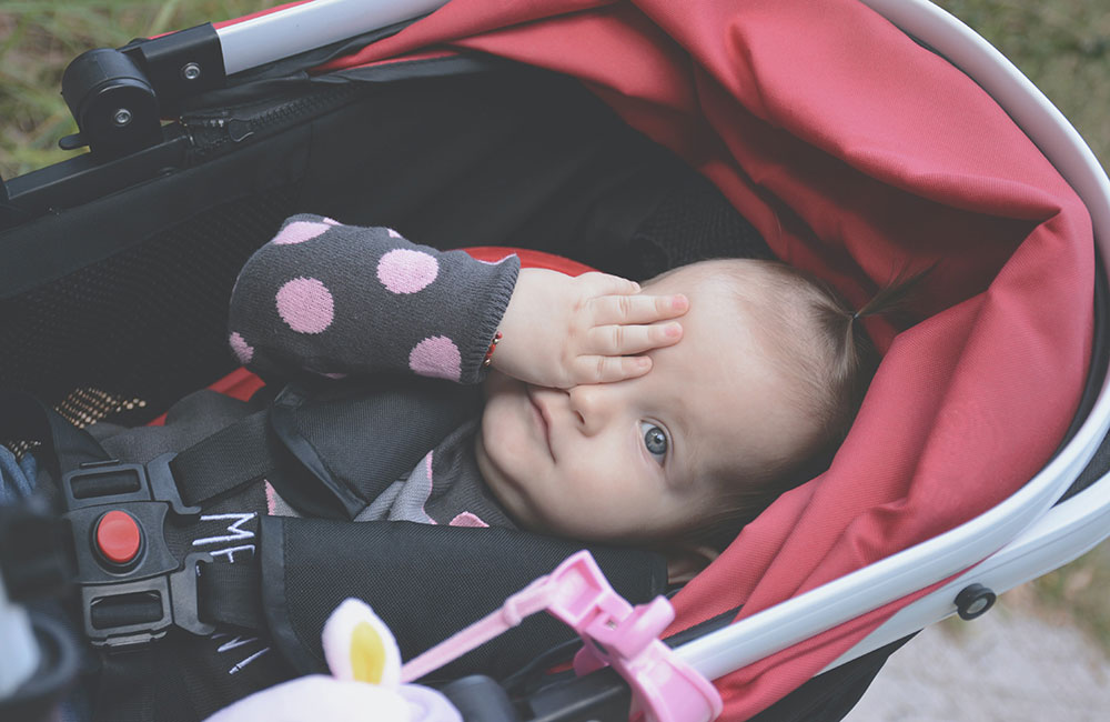 Baby laid in prams with hand over her eye