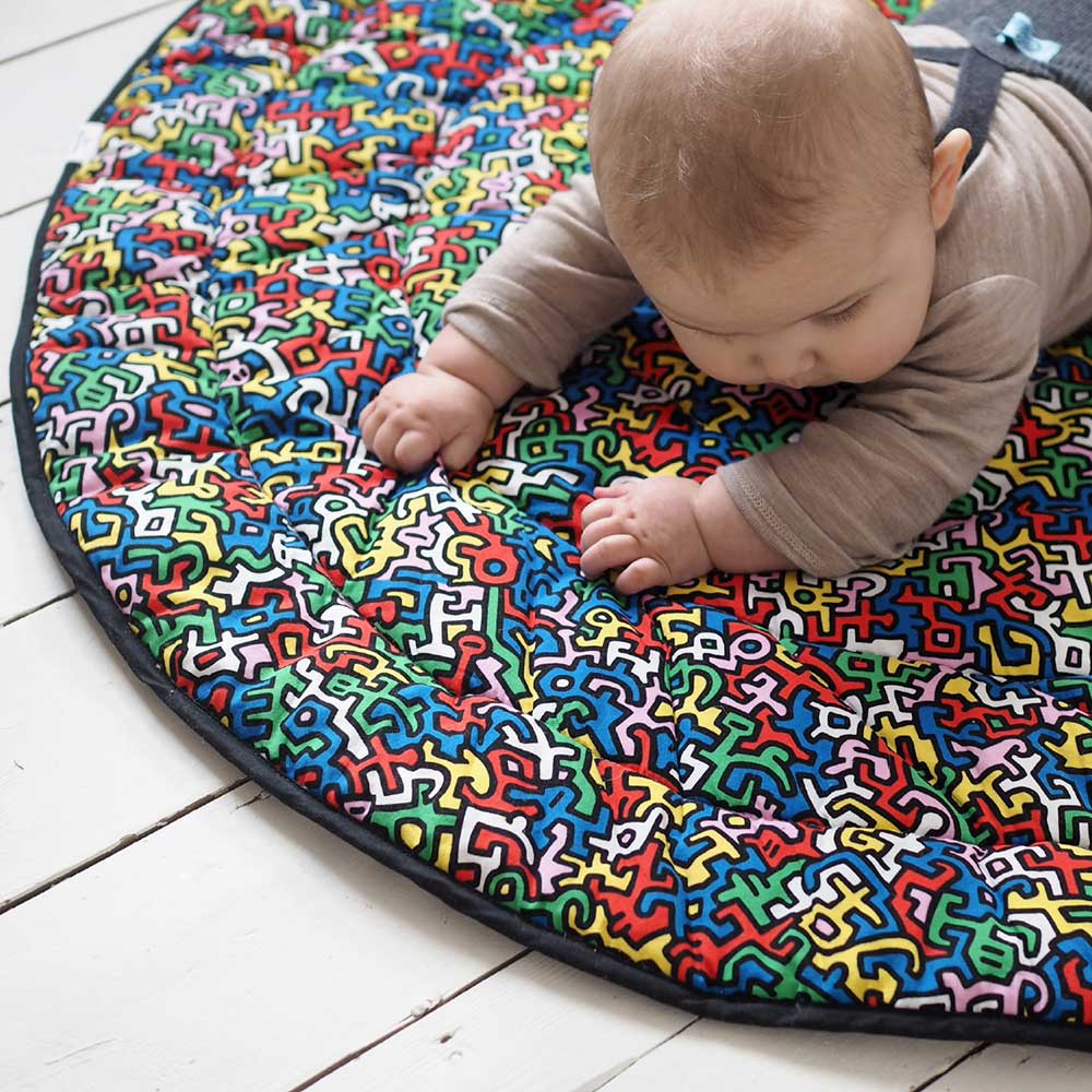 A baby crawling over a reversible playmat
