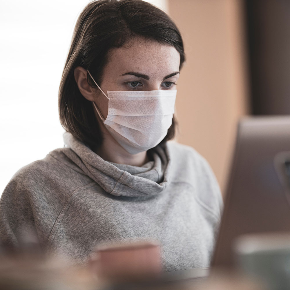Woman in grey jumper with white safety face mask