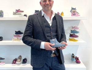 Start-Rite CEO Hugo Adams in grey suit holding a blue kids shoe