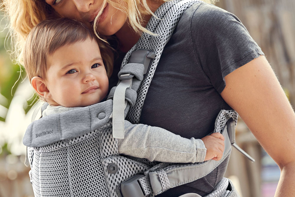 A woman carrying a baby in a baby carrier