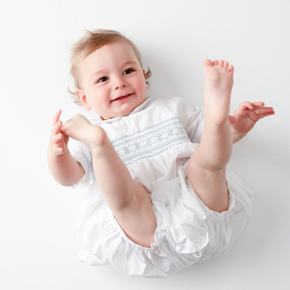 Baby laid with feet in the air in pretty baby gro