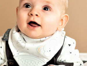 Baby wearing teething bib with Every Cloud print pattern