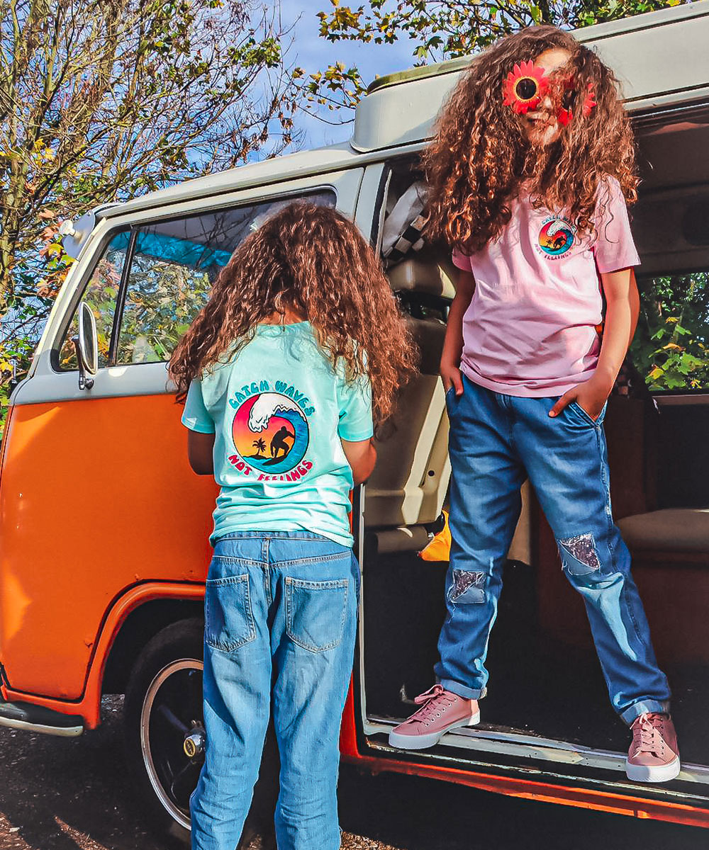 Two girls stood on camper van in Conscious Kidz branded kids wear