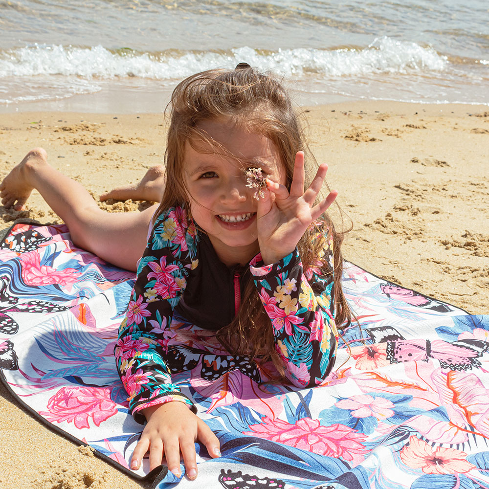 Young girl laid on the beach on Summer beach towel