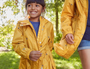Girl in Yelloe Joules rain coat holding her mothers hand