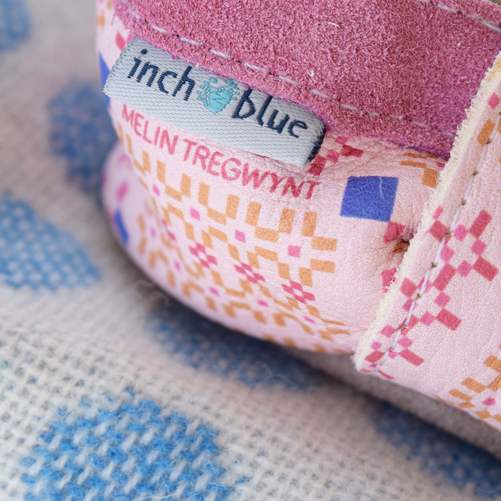 Close up of Inch Blue toddler shoes with tag logo and pink pattern