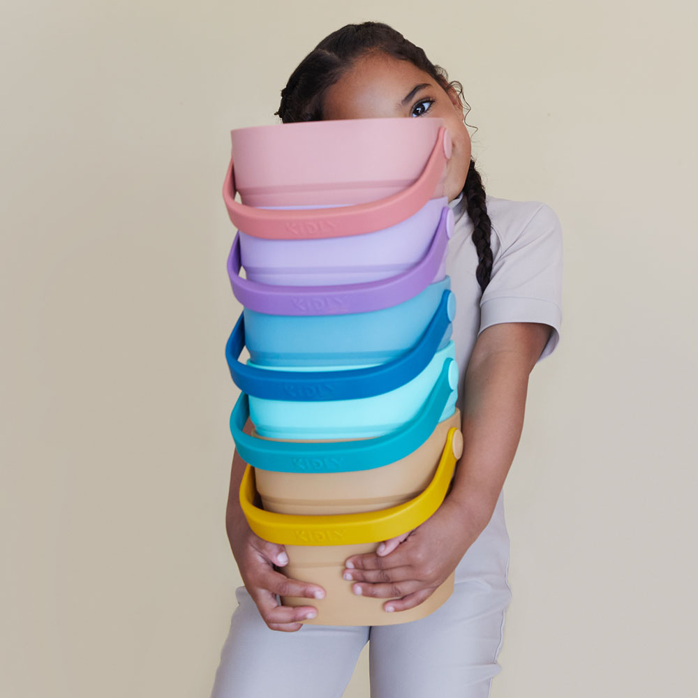 Young girl holding colourful plastic buckets