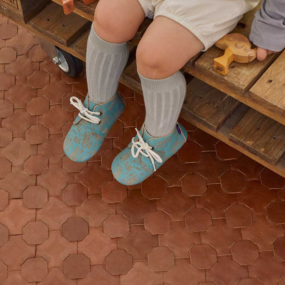 A young toddler sat down wearing Poco Nido footwear