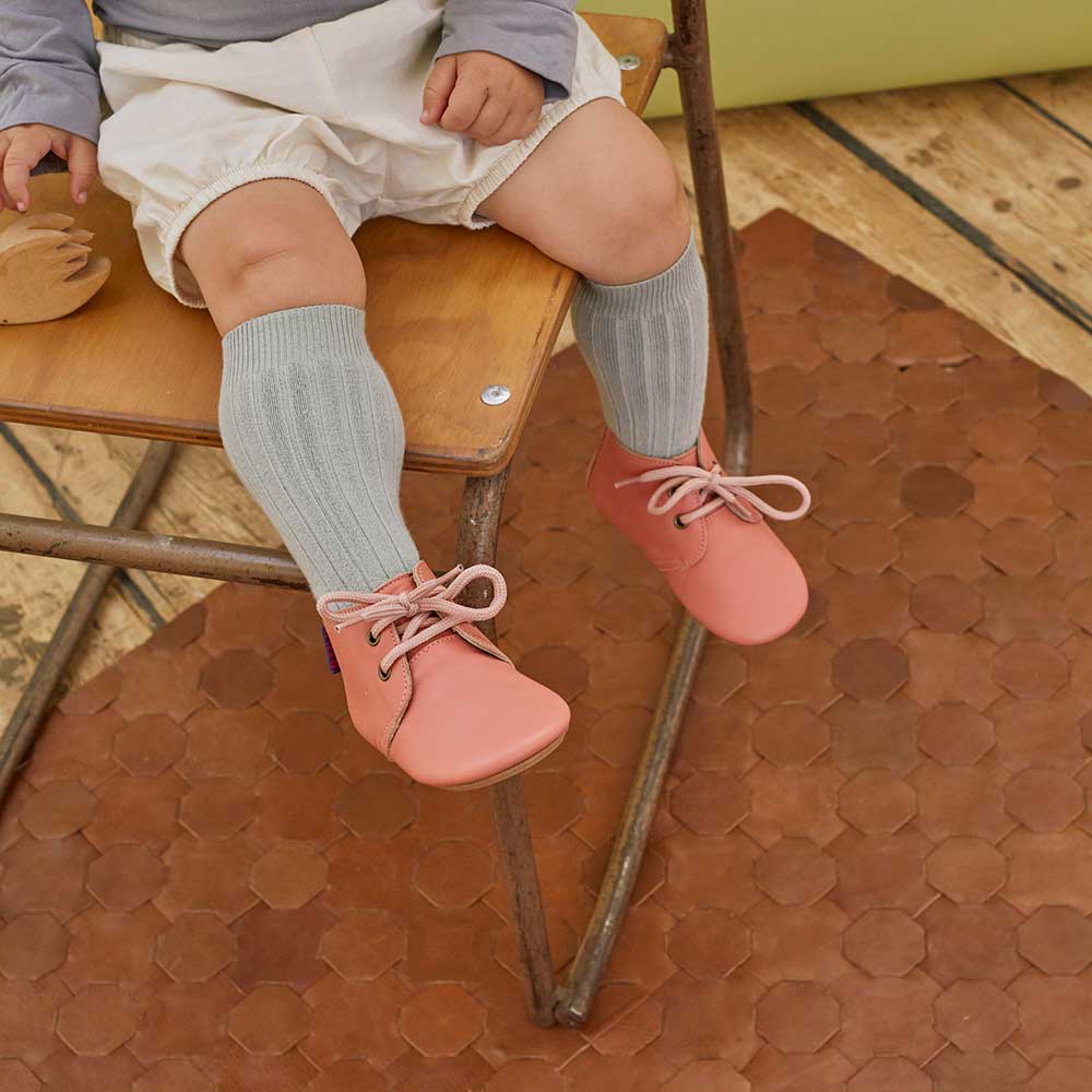 A young toddler sat down wearing Poco Nido footwear