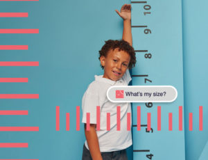 A young boy stood next to a height chart on the wall