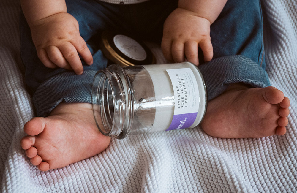 Scented candle in little glass jar between babies feet