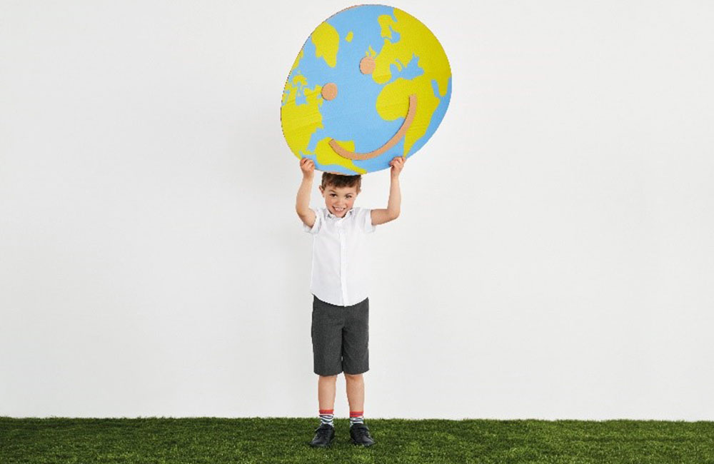 School boy holding up a painting of a globe