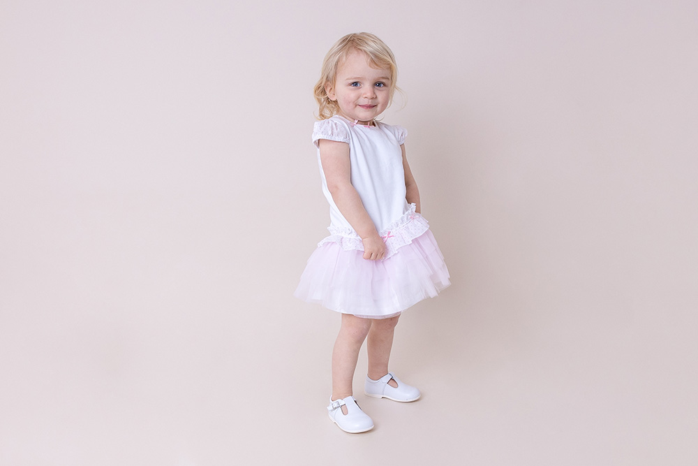 A young girl wearing a pink dress by Pastels & Co