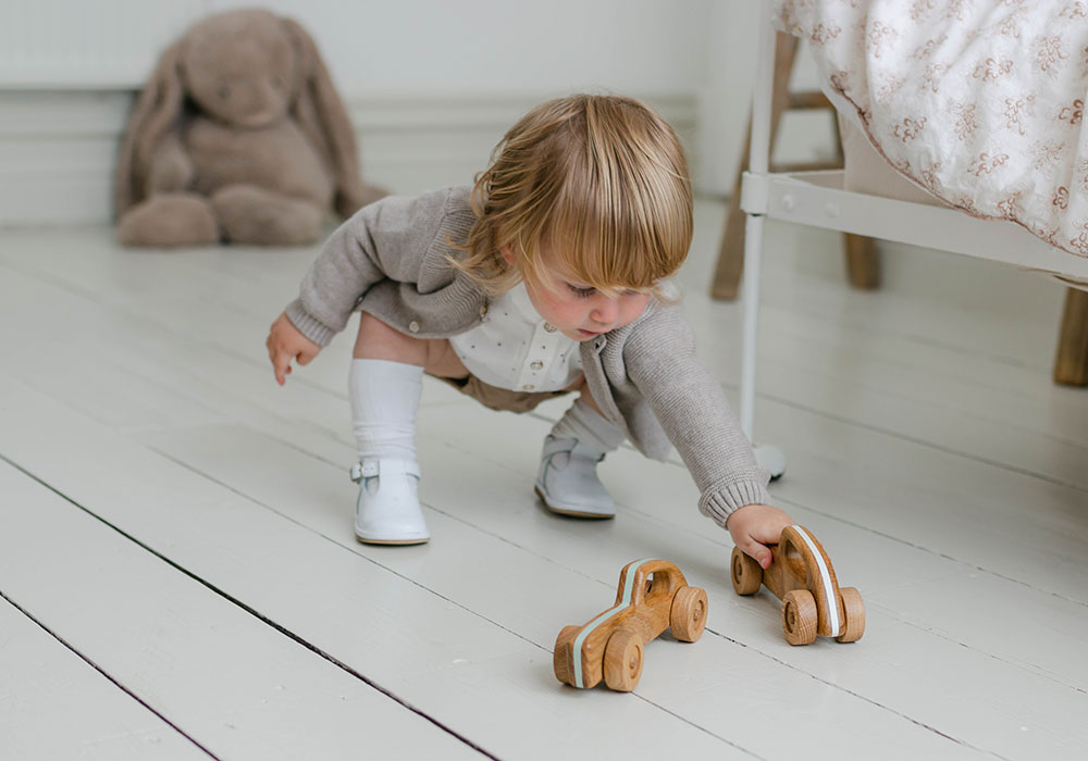 Young boy playing with his handmade wooden toy car