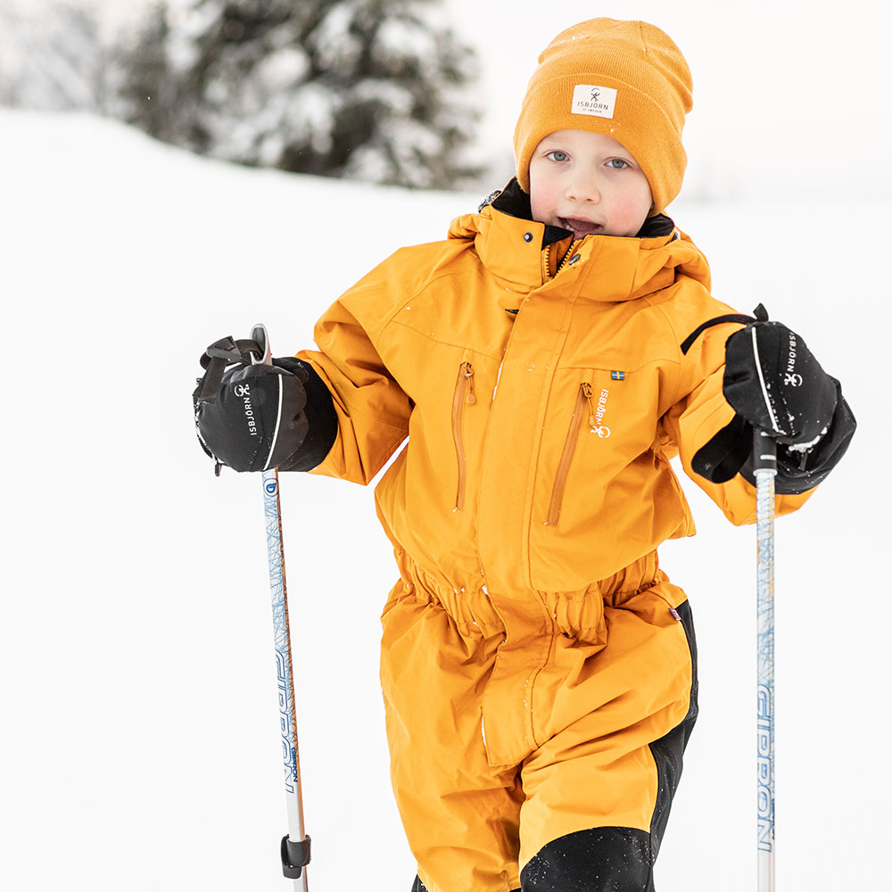 Boy in yellow Penguin Snowsuit with snow behind