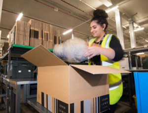 Woman packing a cardboard box at John Lewis Distribution warehouse