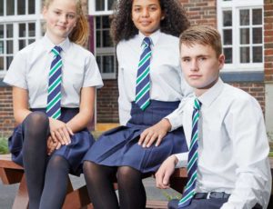 Three students sat outside school wearing school uniforms