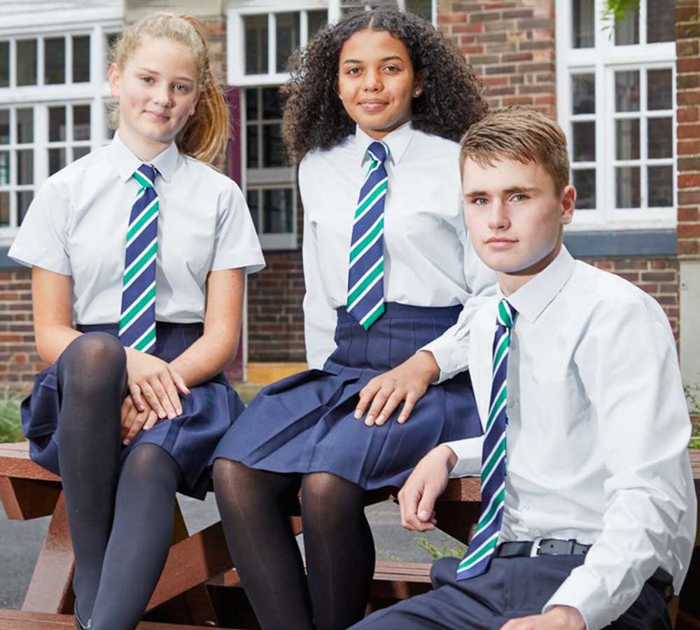 Three students sat outside school wearing school uniforms