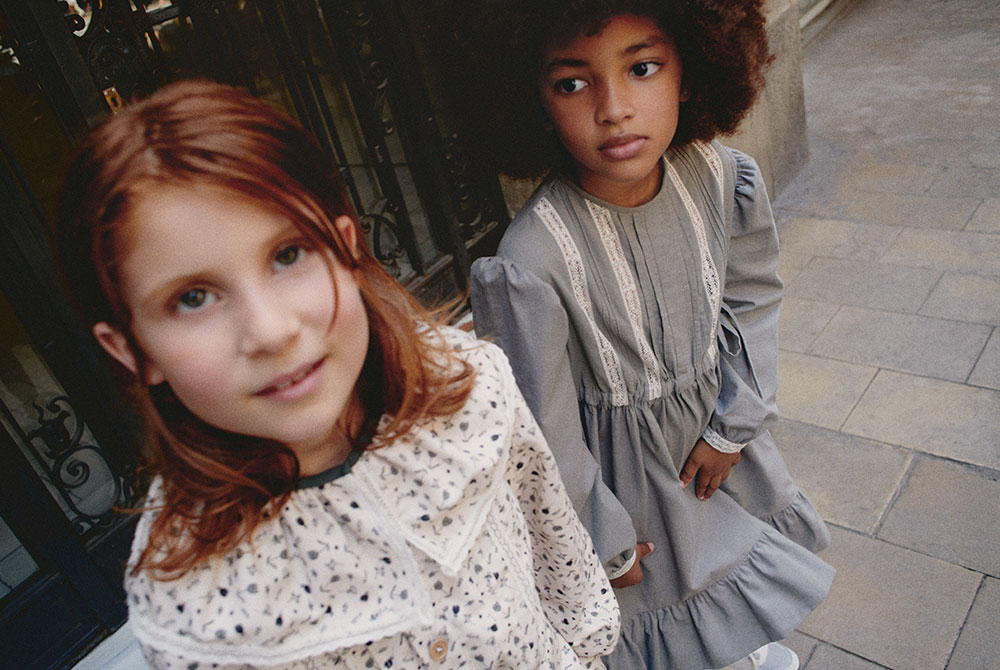 Two young girls wearing vintage style dresses