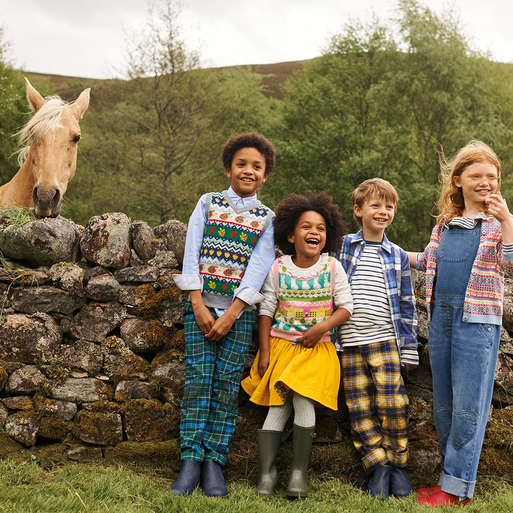 Kids outside wearing Boden clothes for photoshoot as horse looks on