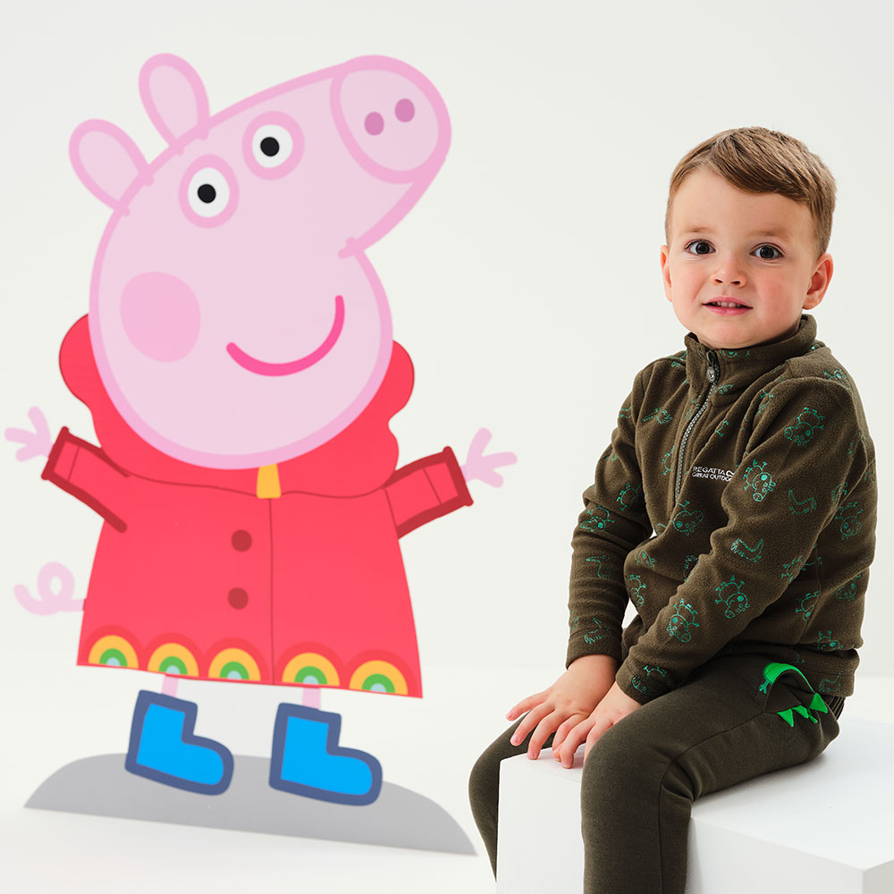 Boy sat next to a colouful illustration of peppa Pig