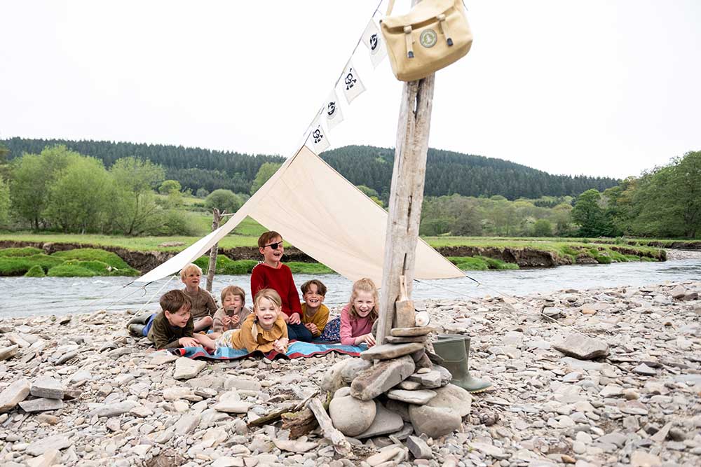 Seven children sat in a tent by a river