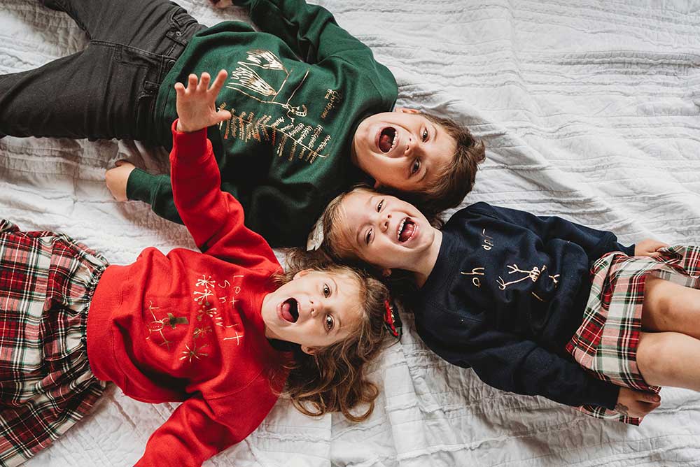 Three children wearing personalised jumpers