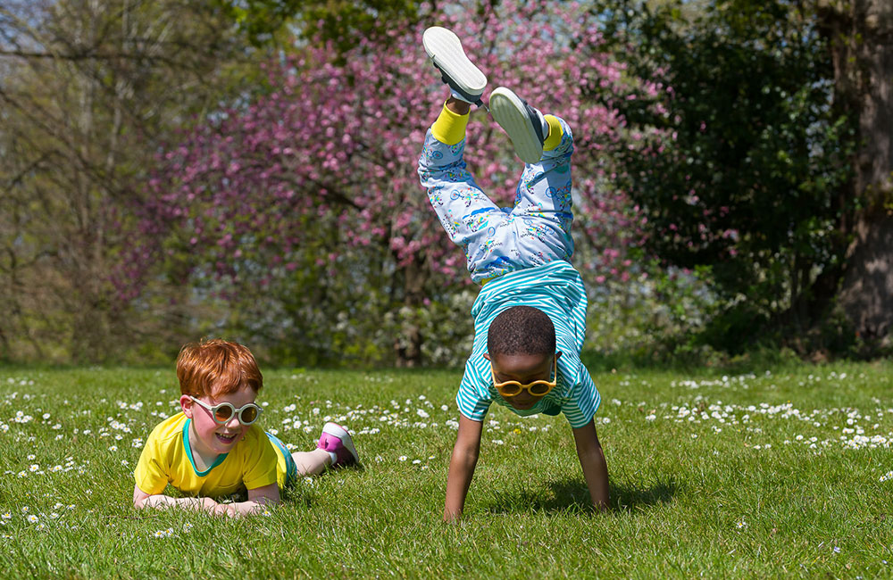 Young boys playing on grass one doing a handstand