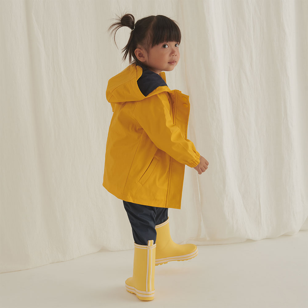 Girl wearing yellow MORI rain coat and wellington boots