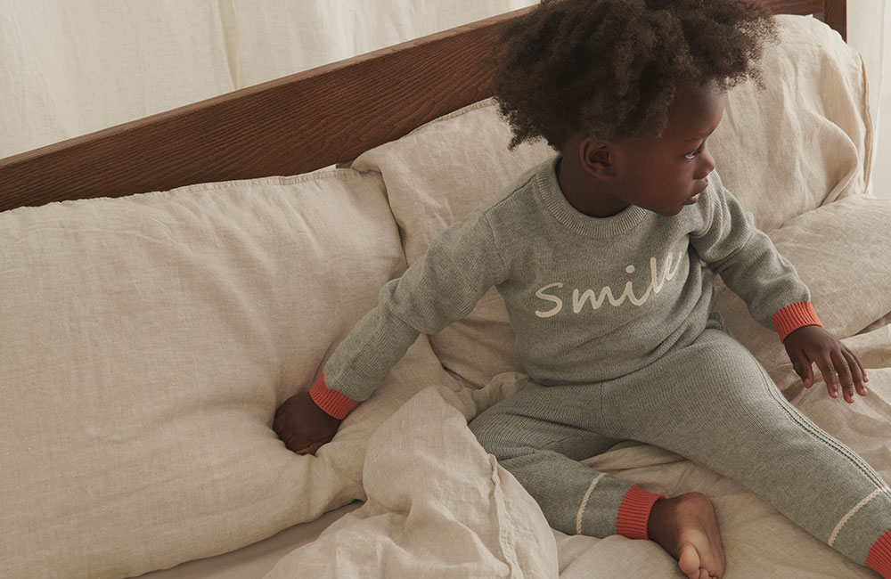 Boy in grey MORI knitted jumper with Smile embroiderd word