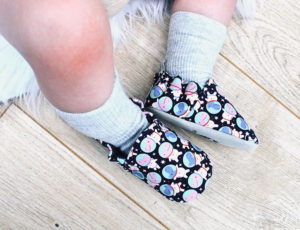 Babies legs wearing black Poco Nido design baby shoes