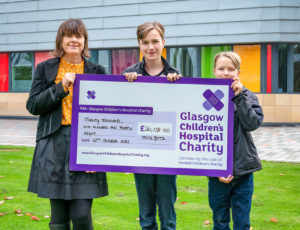 Woman and two children holding a large cheque from TotsBots