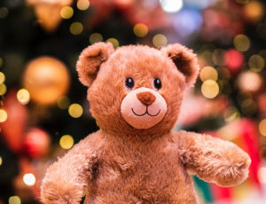 Cuddly teddy bear with christmas tree and lights behind - Wood Street Mission Christmas Appeal 2021