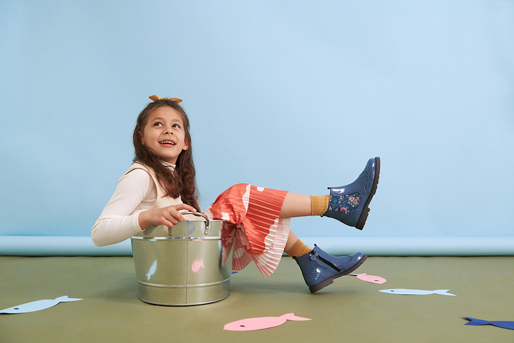A young girl sat in a silver bucket sat on the floor