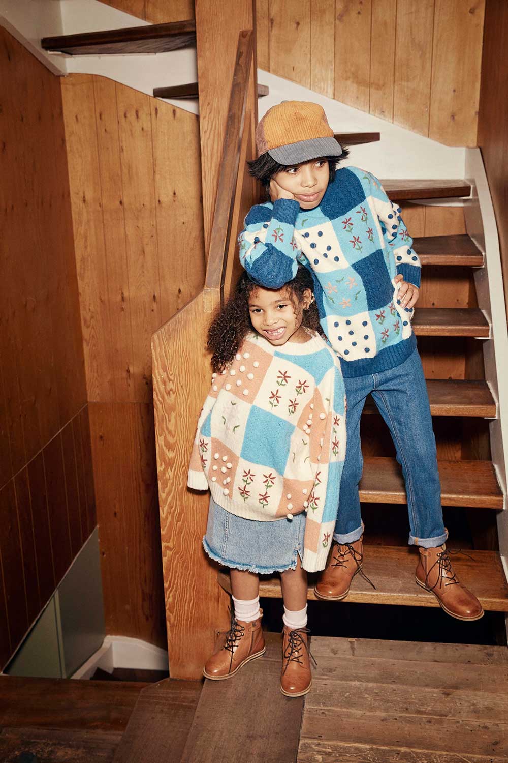 A young boy and girl stood on a wooden staircase