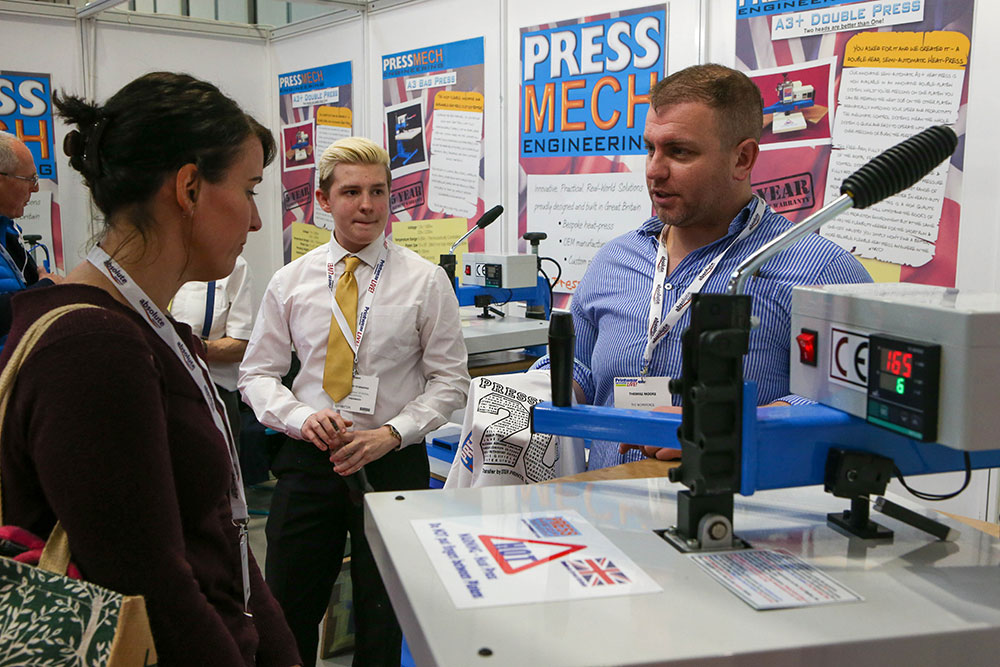 An exhibitor speaking to a visitor at Printwear & Promotion LIVE!