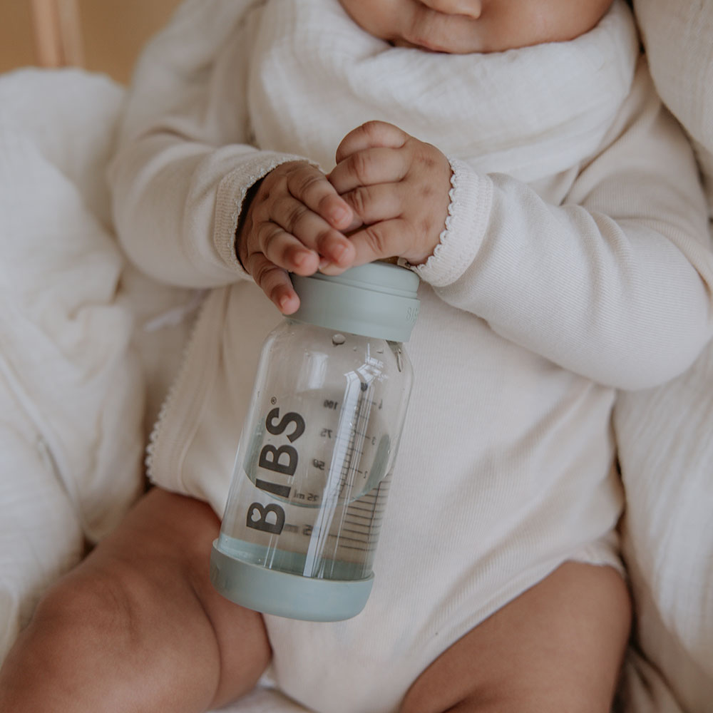 Baby holding glass baby feeding bottle