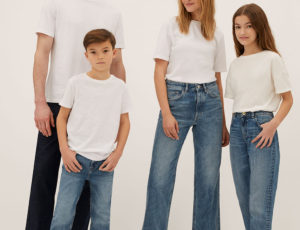 Man, woman, girl and boy stood together wearing blue jeans and white T Shirt