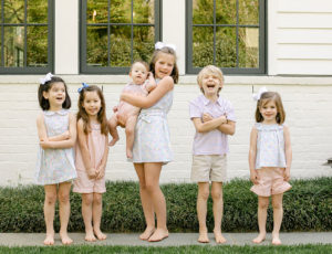 Six children stood on green grass in front of white building with windows wearing Peggy Green