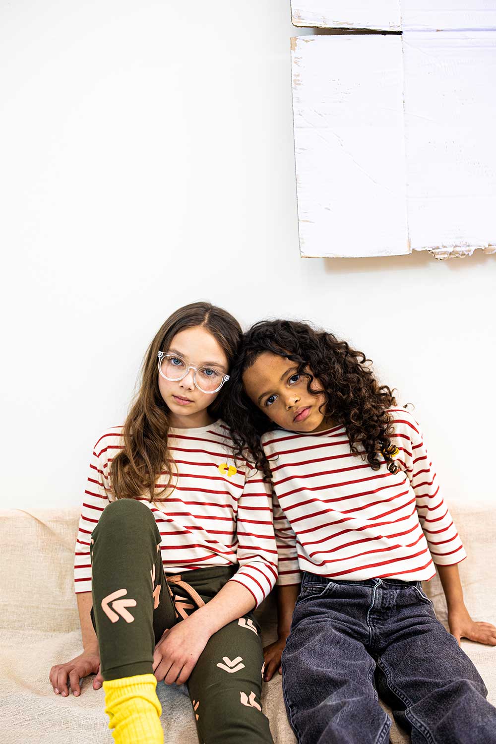 Two girls sat down wearing red striped tops