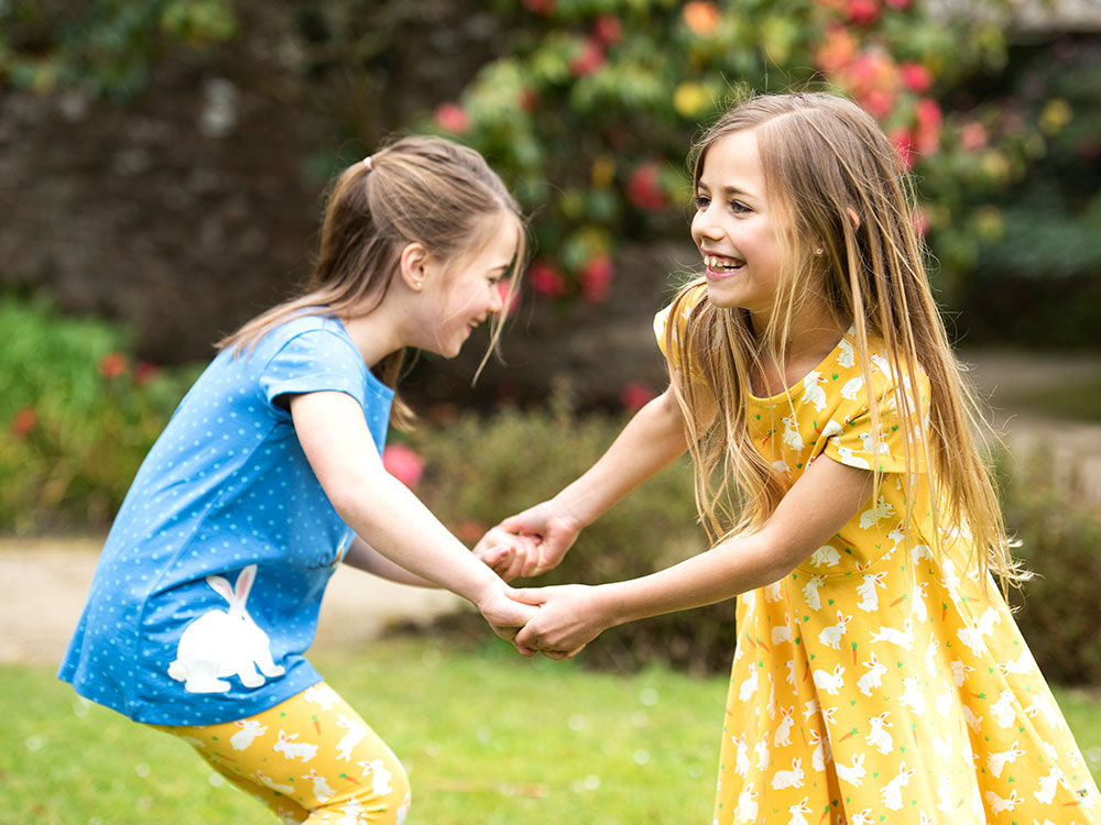 Two young girls holding hands playing outside