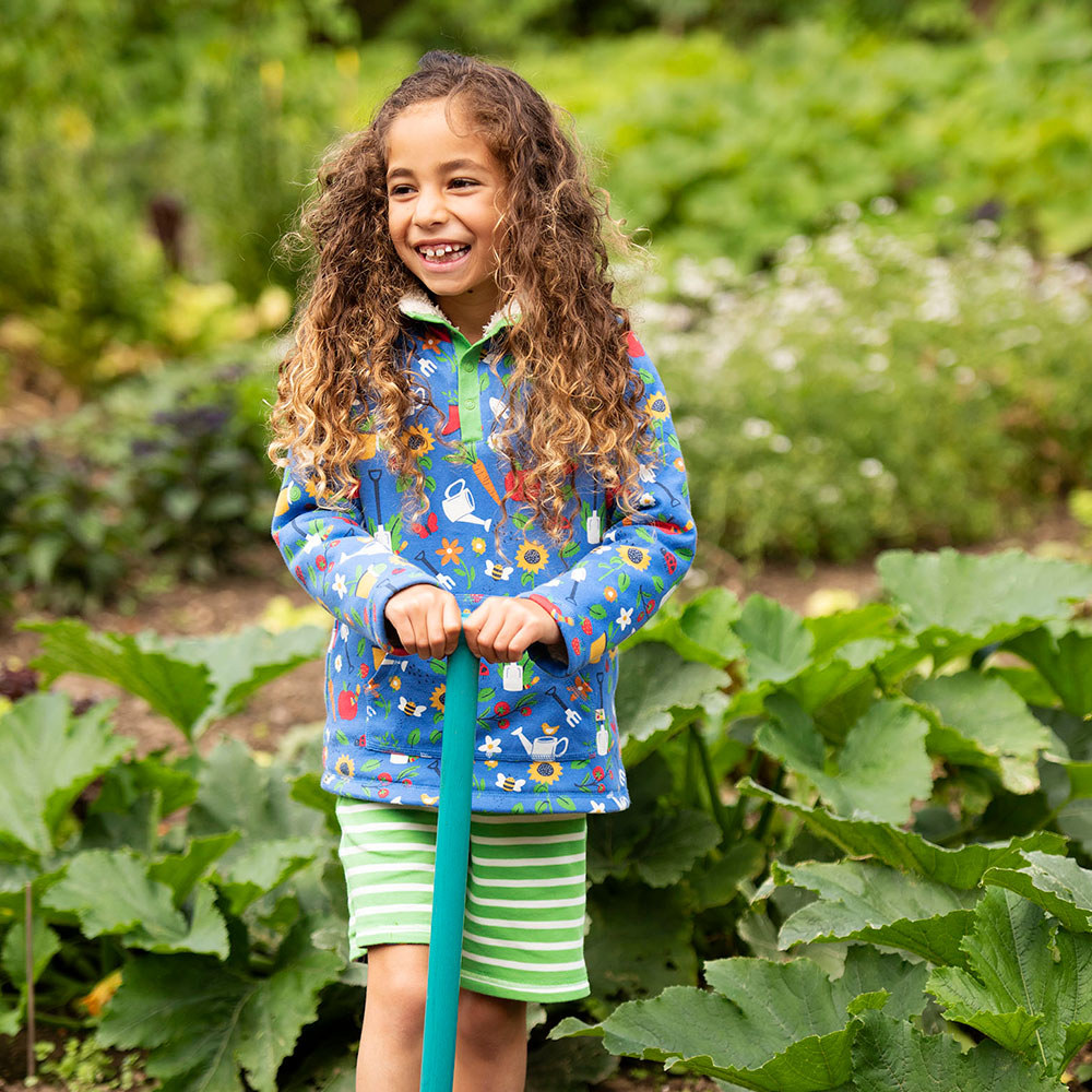 Curly haired girl in garden wearing frugi jumper