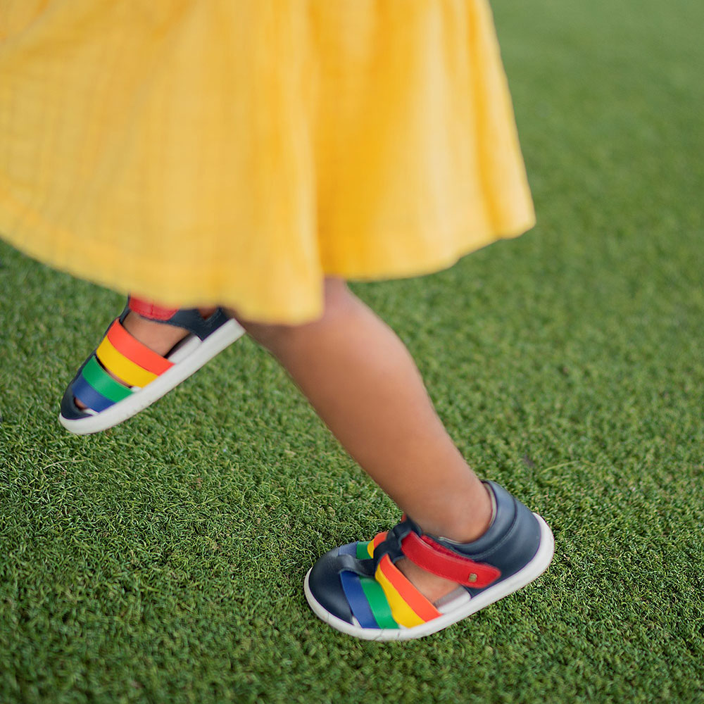 Girl in yellow dress and colourful striped Bobux sandals