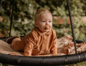 A young boy with a brown pacifier in his mouth